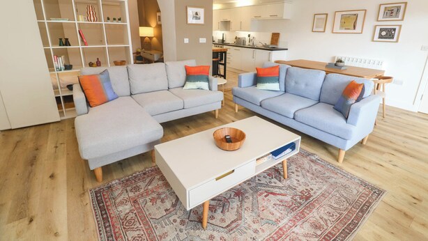 A modern living room with two sofas, a coffee table, and a bookshelf. - 11 Fountain Court (Falmouth)
