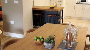 A dining table with a bottle, glasses, and a bowl of fruit. - 11 Fountain Court (Falmouth)