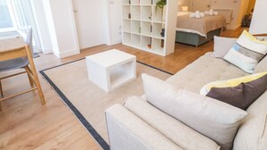 A modern living room with a sofa, a coffee table, and a white shelving unit. - 11 Fountain Court (Falmouth)