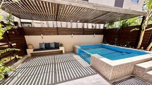 Et poolområde med integreret siddeplads og en pergola over sig.