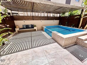 Ein Poolbereich mit integriertem Sitzbereich und einer Pergola darüber.
