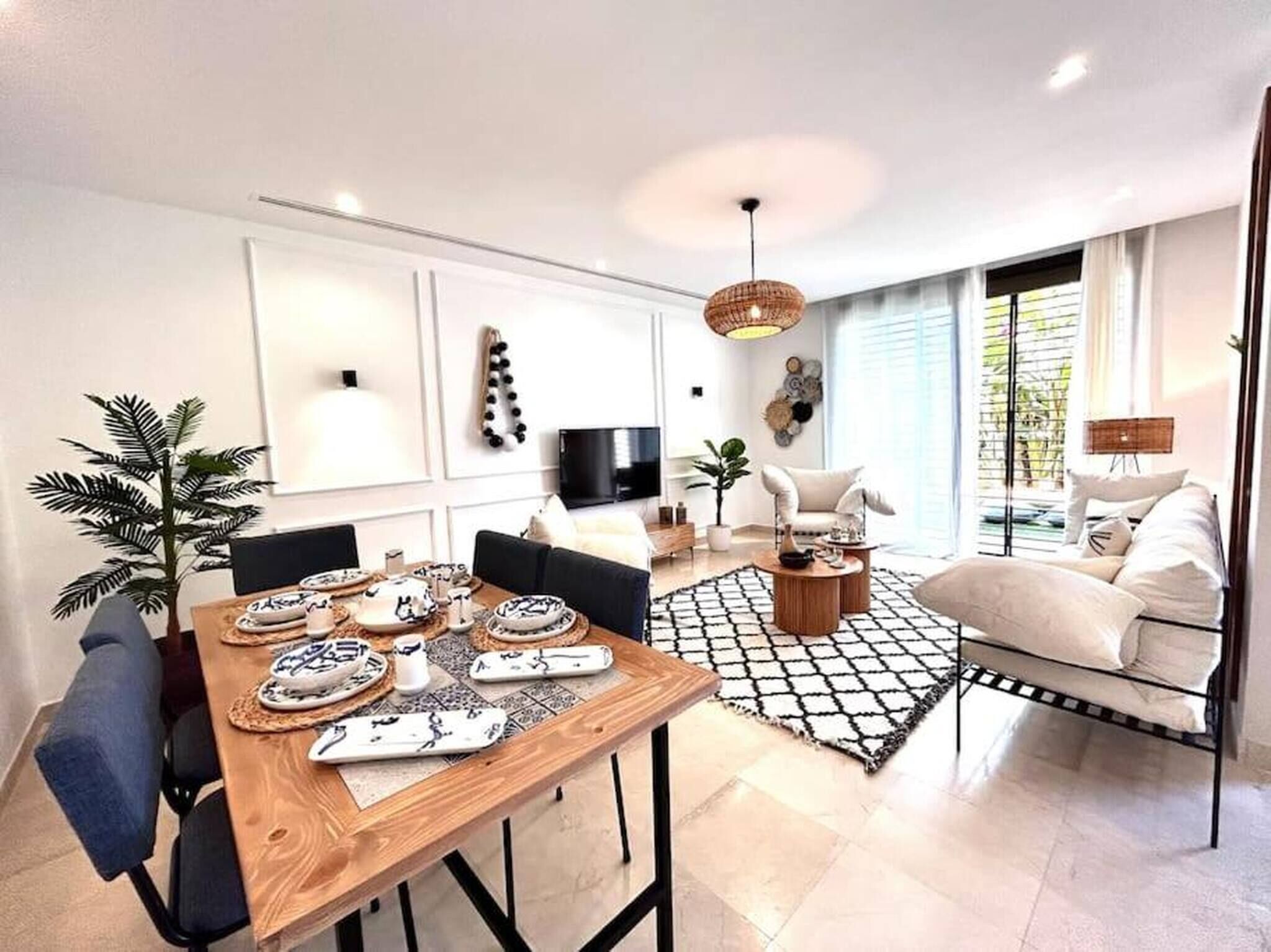 Un salon moderne avec un coin repas, un téléviseur et une grande fenêtre.