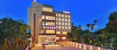 Un hotel con un cartello ben visibile 'GINGER', diversi piani e un'area d'ingresso luminosa con piante in vaso.