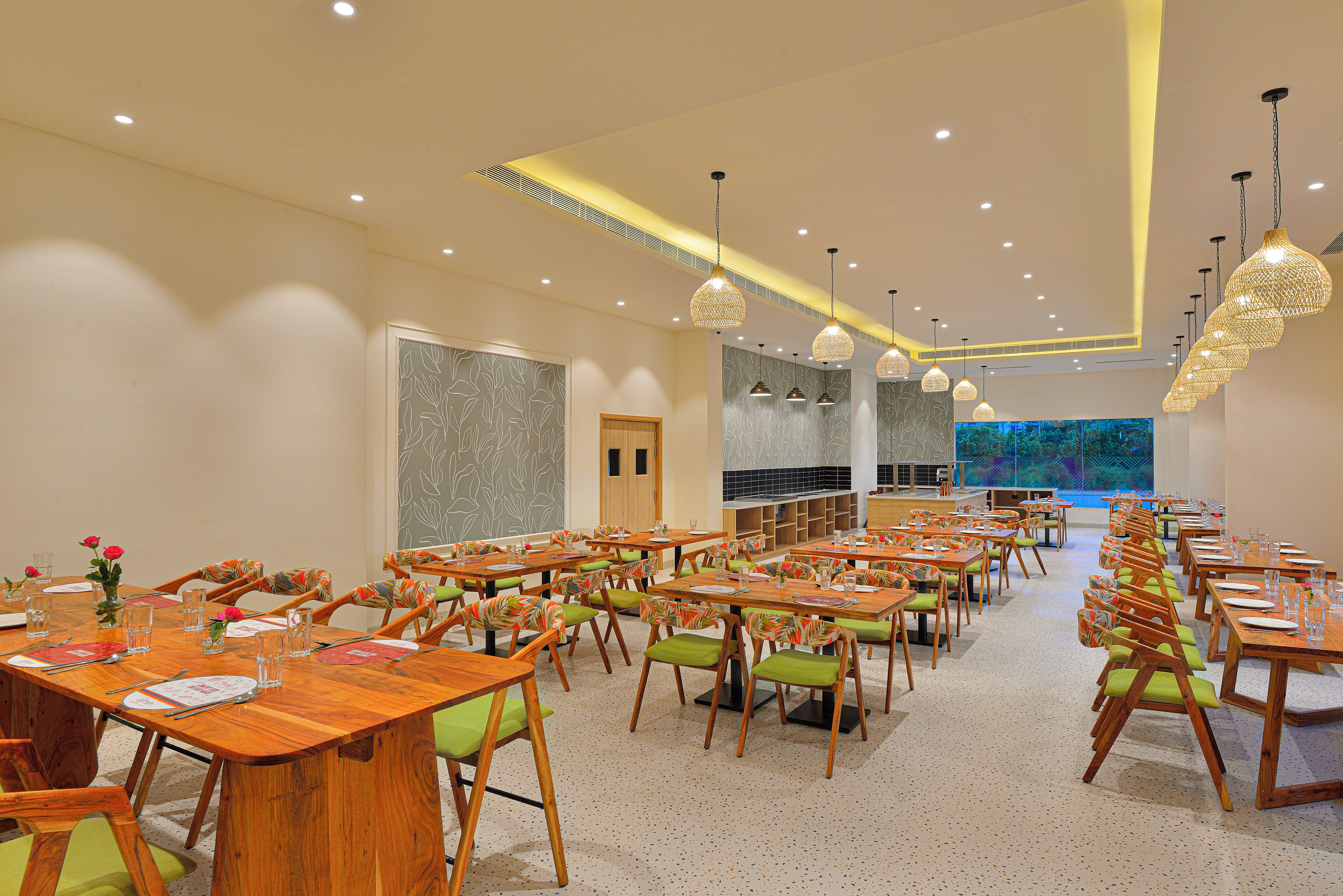 Un comedor amplio con múltiples mesas y sillas, un gran acuario al fondo e iluminación colgante moderna.