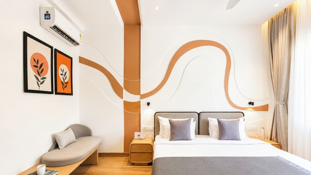 Habitació d'hotel moderna amb llit, taula de nit, zona de seients i obra d'art a la paret.