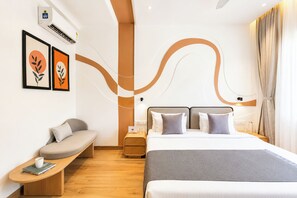 A modern hotel room with a bed, bedside table, seating area, and artwork on the wall. - ELIVAAS Signature Shourya Aravalli 4BHK (Udaipur)