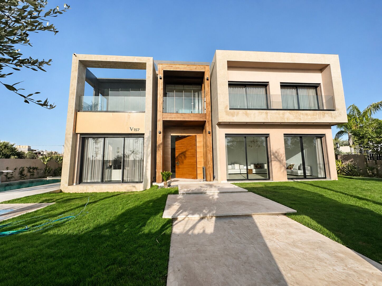 A modern two-story house with a visible address sign, a front entrance, and a well-maintained lawn.