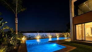 A modern outdoor swimming pool with a clear blue water feature, surrounded by well-maintained grass and plants. - Villa contemporaine - Golf d'Amelkis - Ascenseur et hammam (Marrakech)