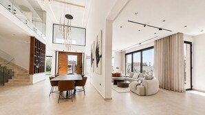 A spacious living area with a dining table, sofas, and a staircase. - Villa contemporaine - Golf d'Amelkis - Ascenseur et hammam (Marrakech)