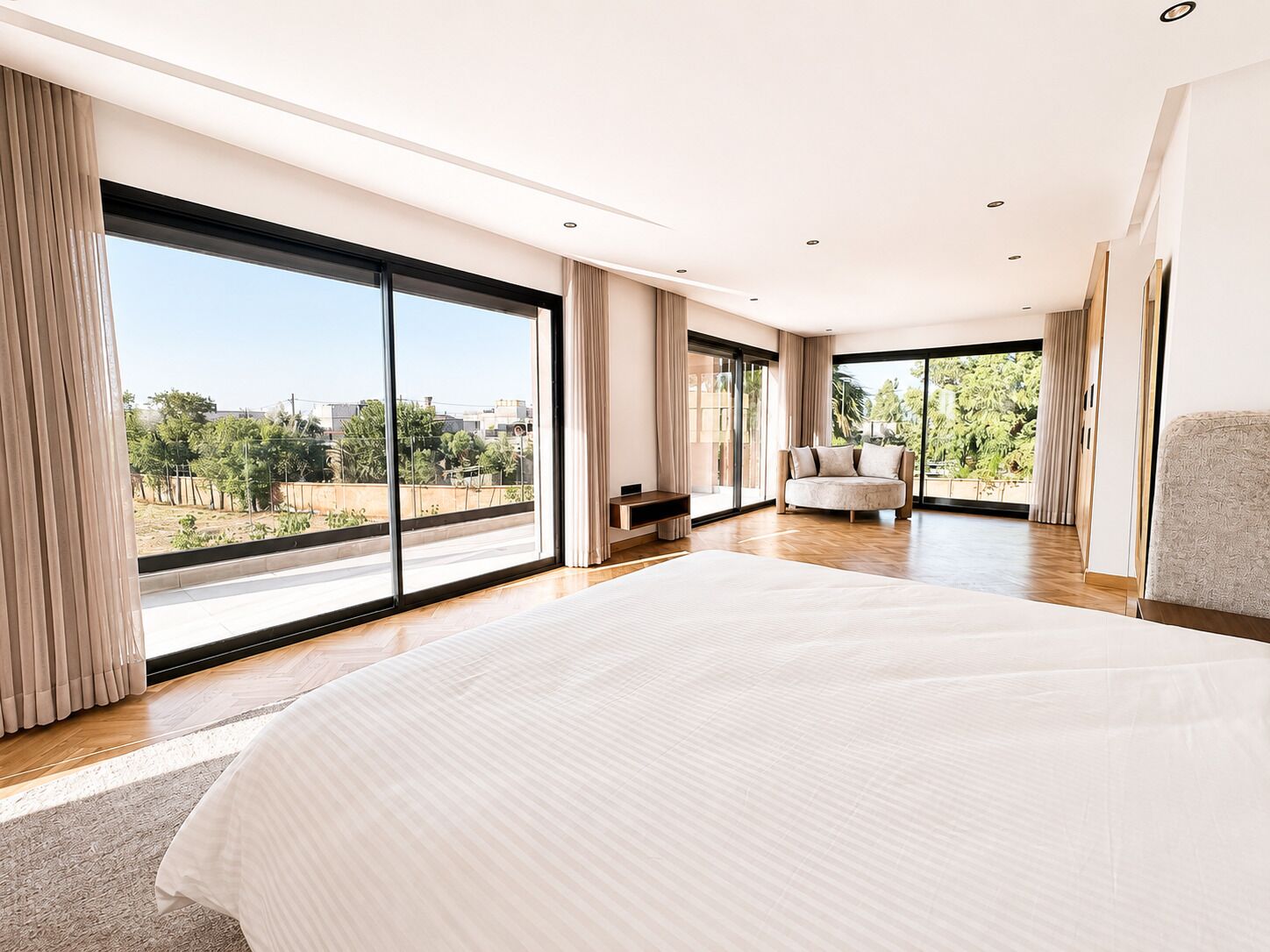 Une chambre spacieuse dotée d’un grand lit, d’un coin salon et offrant une vue sur l’extérieur.