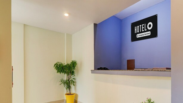 Zona de recepción de un hotel con una pared azul, un cartel que dice 'HOTEL' y una planta en maceta.