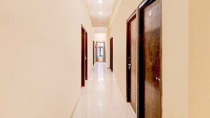 Un pasillo con puertas a ambos lados que conduce a una habitación con ventana.