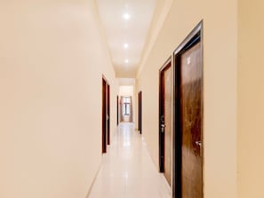 Un pasillo con puertas a ambos lados que conduce a una habitación con ventana.