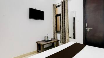 Ein Hotelzimmer mit einem Bett, einem Nachttisch mit Wasserkocher, einem flachbildschirmfernseher an der Wand und einer Tür mit Schloss.