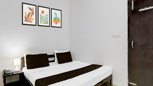 Un dormitorio con cama, mesita de noche, lámpara y tres cuadros en la pared.
