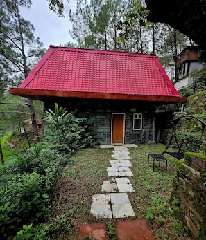 Una casa de techo rojo, pared de piedra y puerta de madera.