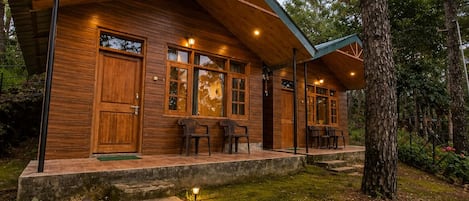 A wooden cabin with a stone pathway leading to the entrance, surrounded by trees.