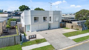Un immeuble résidentiel de deux étages, doté d’un garage, d’une cour arrière clôturée et offrant une vue sur un ciel dégagé.