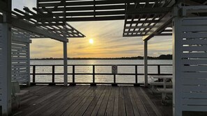 A wooden deck with a railing, a pergola structure, and a view of the water.