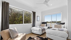 Une chambre moderne avec deux lits, un canapé et un ventilateur de plafond.