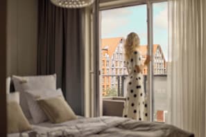 A bedroom with a large window, a bed, and a view of buildings outside. - 154 sqm | Chmielna 63 Penthouse | 3 Bedrooms | AC (Gdańsk)