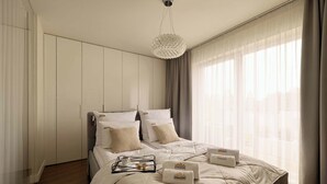 A modern bedroom with a bed, a bedside table, a hanging light fixture, and a window with curtains. - 154 sqm | Chmielna 63 Penthouse | 3 Bedrooms | AC (Gdańsk)
