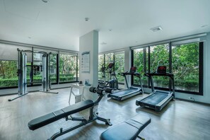 A gym with exercise equipment, large windows, and a view of greenery. - The Title Residencies Naiyang-Electricity & Water Included-E414 (Thalang/Sakhu)
