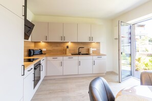 Une cuisine moderne avec des armoires blanches, un plan de travail en bois et un four encastré.