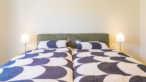 A double bed with a green headboard and two bedside lamps. - Coastal Lodge 33/1 - Just a step from the sea. Sauna. Patio. Garden. (Tossens)
