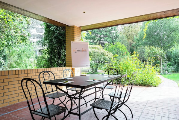 Un patio con una mesa, sillas, una pizarra y vistas a un jardín.