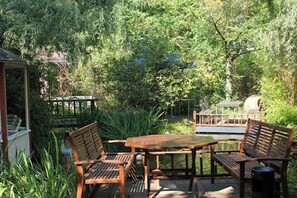 An outdoor patio with a wooden table and benches, surrounded by lush greenery. - TOP Embrace Hotel Grenzfal (Berlin)