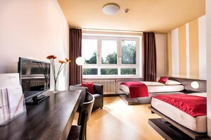 A hotel room with a TV, a desk, a chair, a sofa, and a bed. - TOP Embrace Hotel Grenzfal (Berlin)