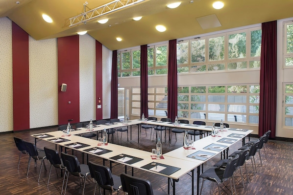 A conference room with a long table, chairs, and large windows with curtains. - TOP Embrace Hotel Grenzfal (Berlin)