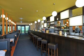 A bar area with high stools, a counter with a cash register, and shelves stocked with bottles. - TOP Embrace Hotel Grenzfal (Berlin)