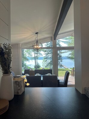 Spisestue med udsigt til en sø, en lysekrone og en vase med blomster.