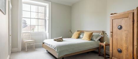A bedroom with a bed, a chair, a wardrobe, and a window.