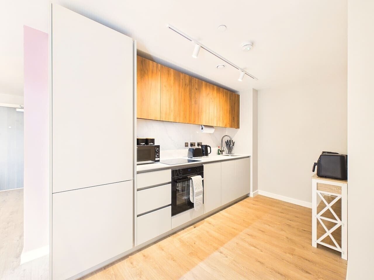 Eine moderne Küche mit weißen Schränken, einer Holz Arbeitsplatte und einem eingebauten Backofen.