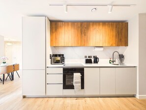 Eine moderne Küche mit weißen Schränken, einer Holzausziehtafel und einem eingebauten Ofen.