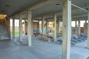 A spacious indoor area with concrete flooring, wooden beams, and a staircase leading to an upper level.