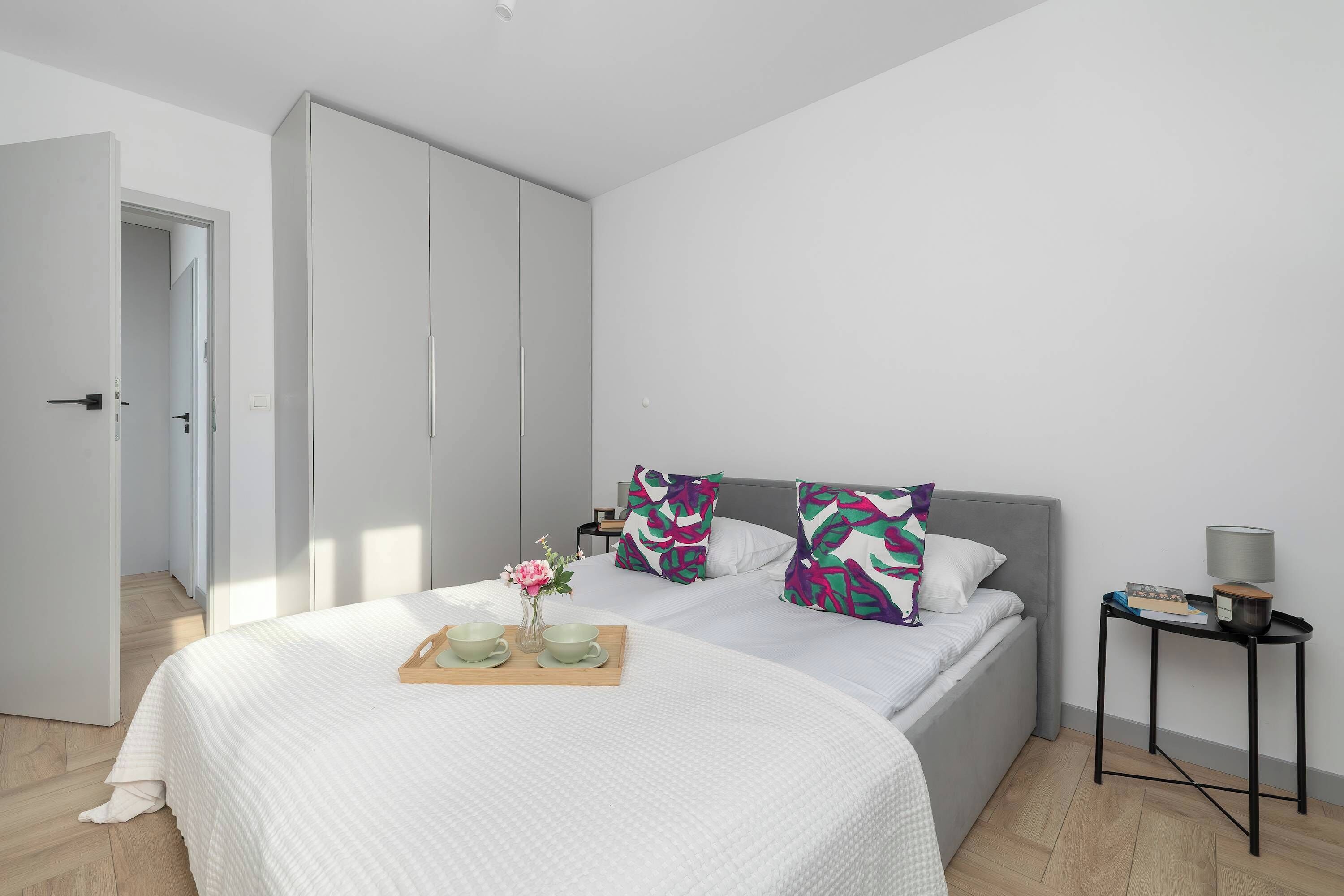 Ein modernes Schlafzimmer mit Bett, Kissen, einem Nachttisch und einem Beistelltisch.