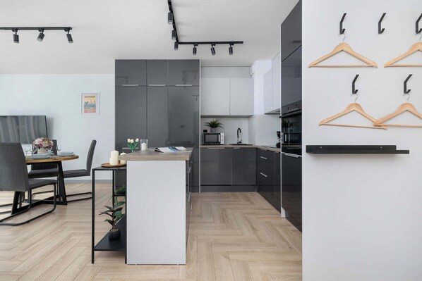 A modern kitchen with dark cabinets, a wooden dining table, and a small island.