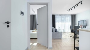 Un apartamento moderno con piso de madera, una cama, un comedor con mesa y sillas, y una sala de estar con sofá y televisor.