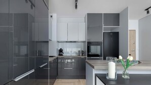 Una cocina moderna con muebles oscuros, horno empotrado y cafetera sobre la encimera.