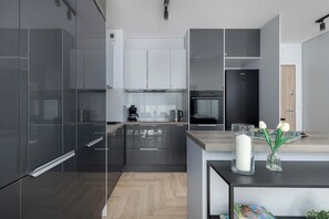 A modern kitchen with dark cabinetry, a built-in oven, and a coffee maker on the counter.