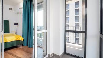 A hotel room with a bed, a window, and a view of a building.