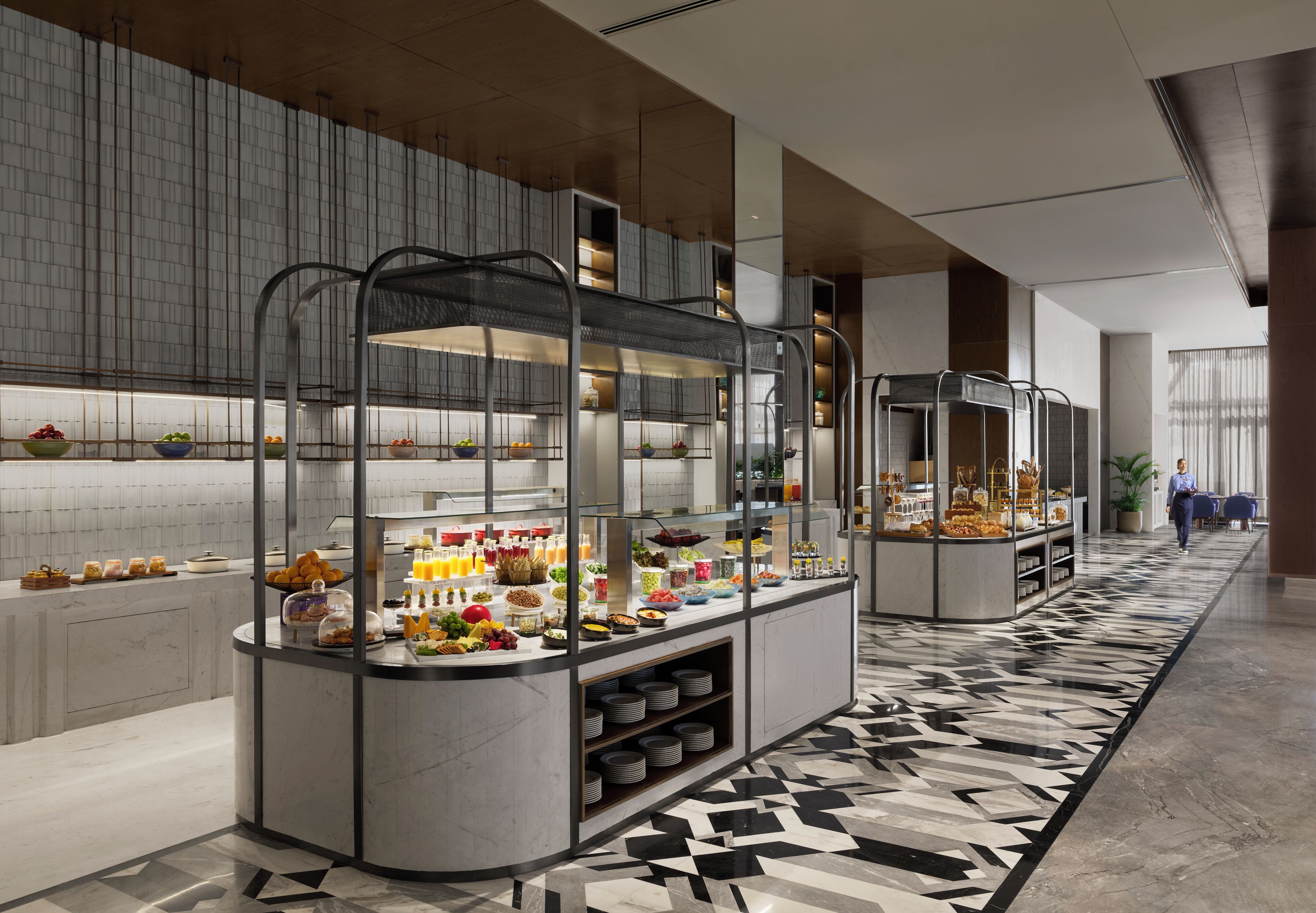 Un área de desayuno de hotel moderna con estaciones de autoservicio, pisos de mármol y un diseño contemporáneo y limpio.