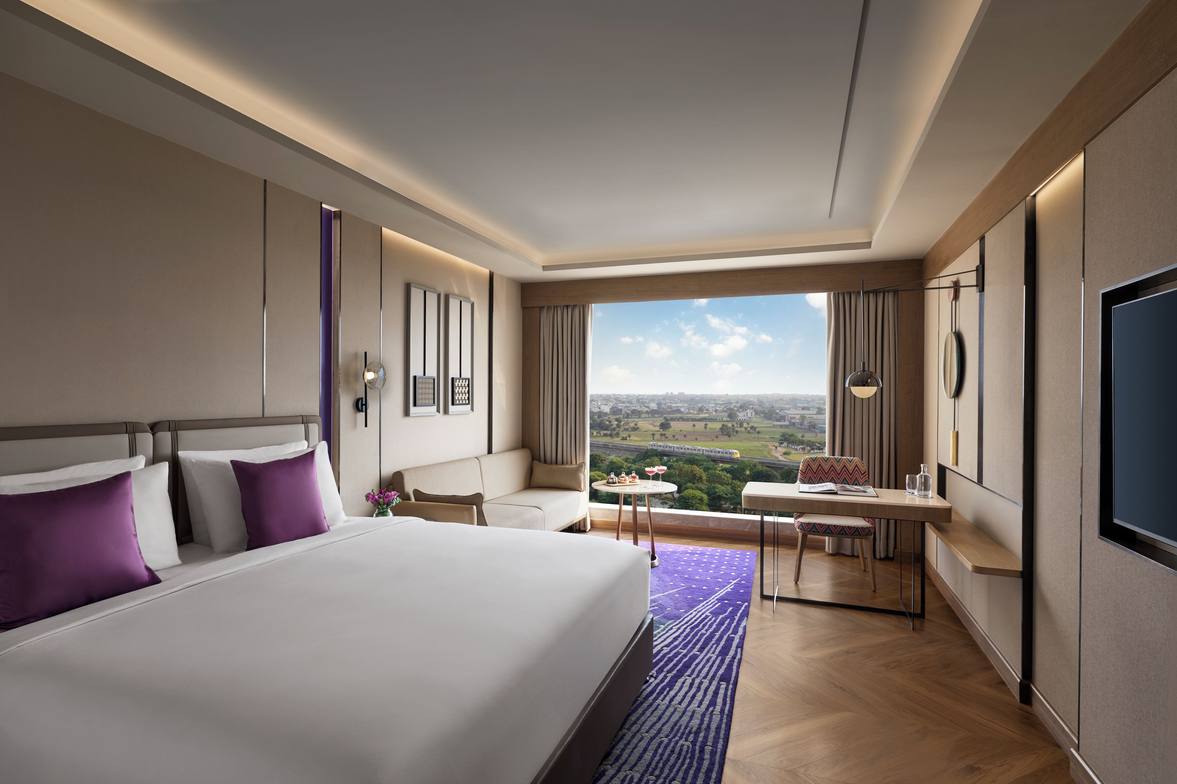 A hotel room with a large bed, a desk, and a view of the city.