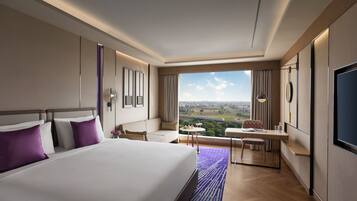 A hotel room with a large bed, a desk, and a view of the city.