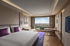 A hotel room with a large bed, a desk, and a view of the city.