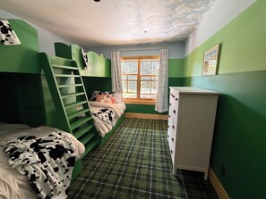 A room with a bunk bed, a dresser, a window with curtains, and a plaid carpet.